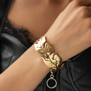 Close-up of golden leaf pattern cuff bracelet with detailed texture on female wrist