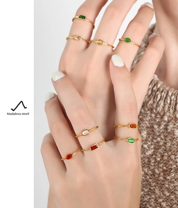 Detail of stacked gold plated stainless steel rings with multi-colored gemstones