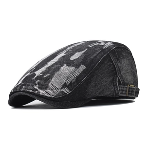 Close-up of distressed denim ivy cap featuring artistic torn details and a metal side buckle