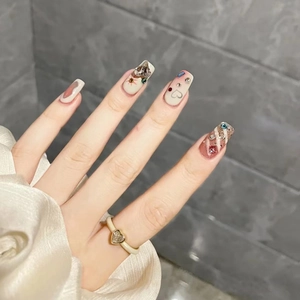 Nude milky white press-on nails with heart charms, colorful rhinestones, and glitter finish