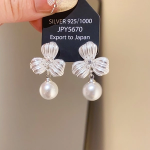 Detail of 925 silver flower earrings with small diamond and elegant hanging pearl pendant