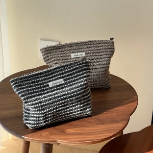Detail of tweed makeup bags with Simple Wish tags on a dark wood table with natural lighting