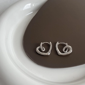 Close-up of silver-plated twisted heart earrings on a premium leather display pad