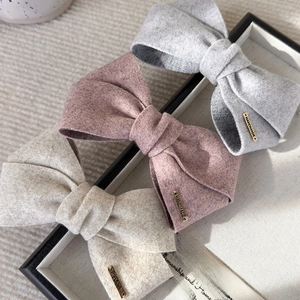 Three velvet handmade bow hair clips in grey, pink and beige with gold metal accents