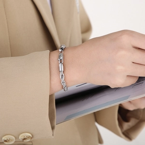 Close-up of a silver twist rope bracelet with a lobster clasp worn on a model wrist