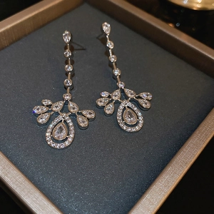 Macro shot of silver drop tassel earrings with sparkling zircons on velvet