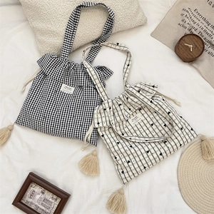 Close-up of sweet plaid and heart canvas tote bags with drawstring and tassel details