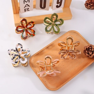 Chic multi-color floral hair claws on wooden tray with cozy home decor setting