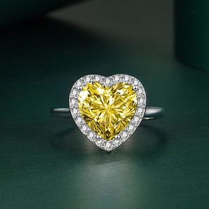 Vue macro d'une bague coeur en zircon jaune avec sertissage halo sur fond vert mat