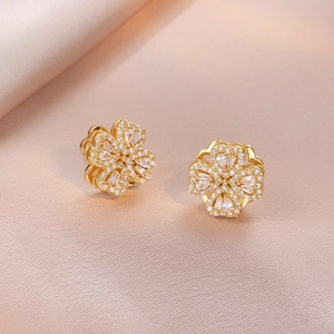 Close-up of gold-plated clover earrings with micro-pave zircons on silk fabric