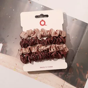 Detail of 4-pack satin scrunchies in brown and champagne gold on card packaging