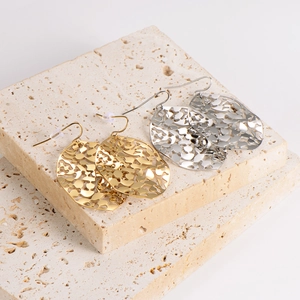 Modern hollow leaf geometric earrings in gold and silver finish on stone pedestal