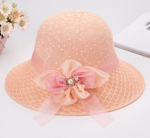 Dettaglio cappello di paglia da donna con fiore in chiffon rosa, perle e nastro decorativo