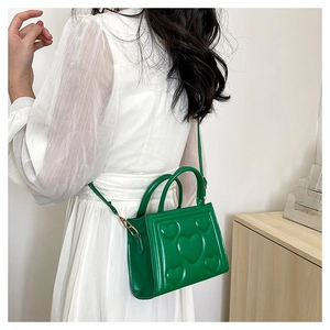 Détail du sac bandoulière en cuir PU vert avec gaufrage cœur porté par un mannequin
