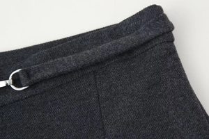 Detail von dunkelgrauem Twill-Stoff mit feinen Nähten und silberner Metallschnalle