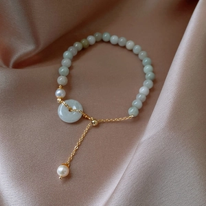 Detail of jade bead bracelet with pearl accent and gold slide clasp on silk