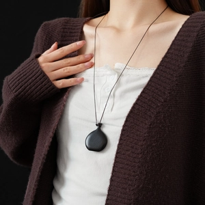 Detail of a minimalist black wooden wine gourd pendant necklace on a matching silk cord