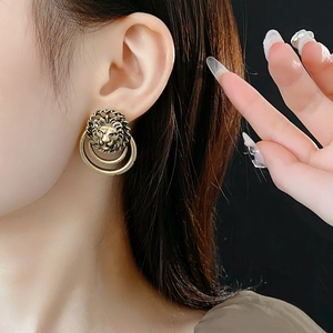 Détail de boucles d'oreilles tête de lion vintage avec doubles anneaux en bronze