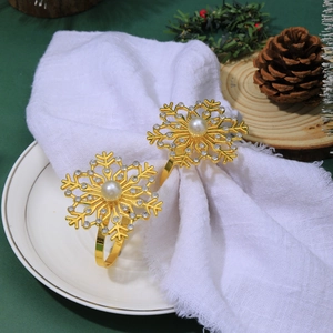 Detailed view of two gold snowflake napkin rings with pearls and rhinestones