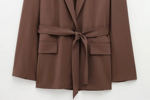 Detail of brown belted blazer jacket with notched lapels and flap pockets in twill fabric