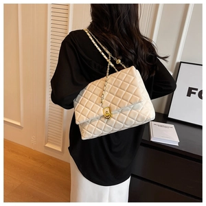 Detail of white quilted leather texture and gold woven chain strap on a women's shoulder bag