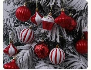 Close-up of assorted red and white Christmas ornaments hanging on snowy pine branches