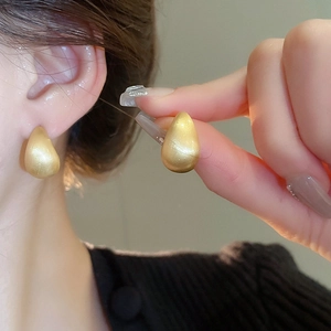 Detailed view of matte gold water drop earrings showing elegant brushed metal texture