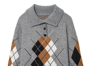 Dettaglio di un maglione polo in maglia grigia con motivo a rombi e colletto a costine