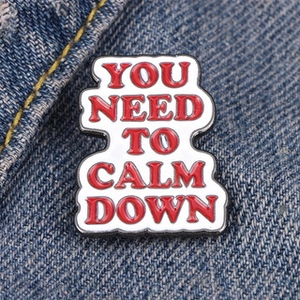 Minimalist enamel pin brooch with red text YOU NEED TO CALM DOWN on denim jacket