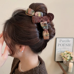 Detailed view of an acrylic flocked bow hair claw clip in colorful knitted fabric on hair