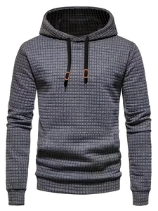 Detailed macro view of gray waffle knit fabric texture and leather patch on men's hoodie