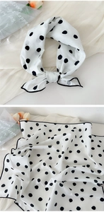 Detail of white cotton linen scarf with black polka dots showing knot and texture