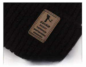Detailed close-up of a black knit beanie with a brown leather logo patch and texture