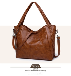 Detail of brown tote bag with woven handles, V-stitching and decorative tassel