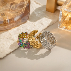 Braided iridescent and gold stainless steel open rings displayed on artistic paper