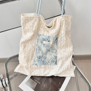 Detailed close-up of white lace fabric texture and floral pocket on the canvas tote bag