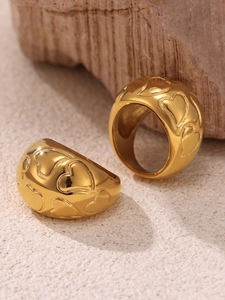 Macro shot of 18k gold plated stainless steel rings with embossed heart pattern on rock