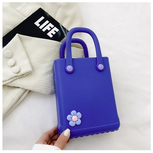 Draufsicht auf hellblaue EVA Strandtasche mit Blumenanhänger neben einem Magazin