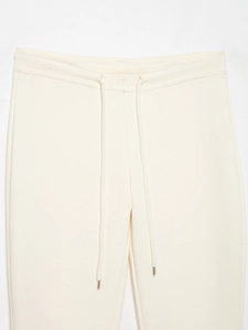 Détail de la taille élastique avec cordon de serrage sur un jogging blanc crème