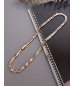 Close-up of gold tennis necklace with baguette zircon stones and box clasp detail