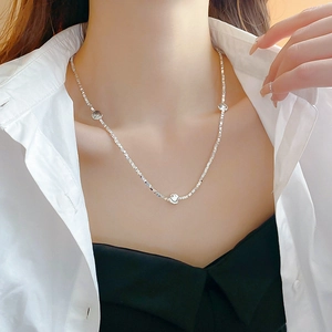 Close-up of a silver smiley face necklace worn by a model in a minimalist style