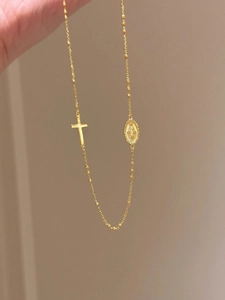Détail du collier en chaîne fine dorée avec croix et pendentif médaille miraculeuse
