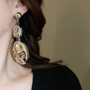Detail of silver metallic irregular earring with textured surface on a model side view