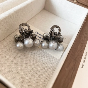 Macro shot of silver metal bow hair clips with white pearls in a wooden jewelry box