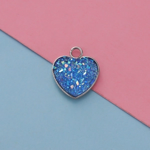 Macro view of blue glitter resin heart pendant with silver metal frame and jump ring