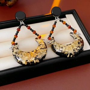 Close-up of vintage crescent moon earrings with resin gold leaf texture in a black box