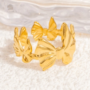 Detailed view of a golden bow ring with textured finish on soft white plush fabric