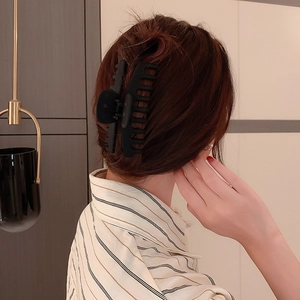 Gros plan d'une grande pince à cheveux géométrique noire mate sur les cheveux d'une femme