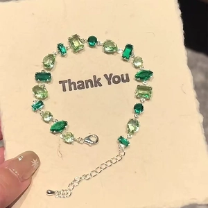 Macro view of multi-shaped green gemstones and adjustable silver chain on a bracelet