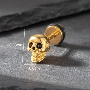 Macro shot of gold skull stud earring with size dimensions on a dark stone background